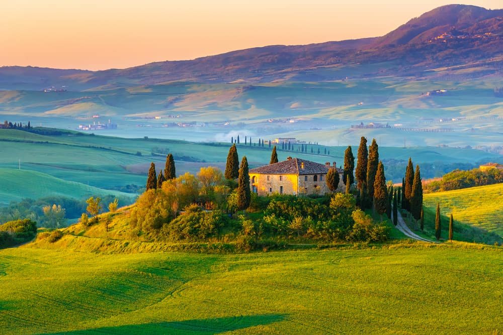 stunning landscape of tuscany - classic italian home surrounded by trees with hills in thre distance - romantic things to do in tuscany